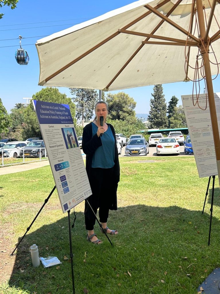 Woman presenting her poster, staying on grass